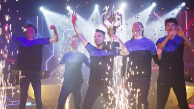 Erkek oyuncular havai fişek yakınlarında zaferi kutluyorlar