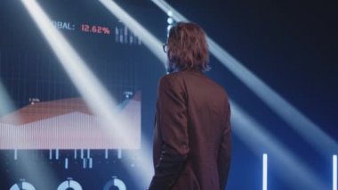Ciddi bir işletme koçu LED ekranda çizelgeleri izliyor