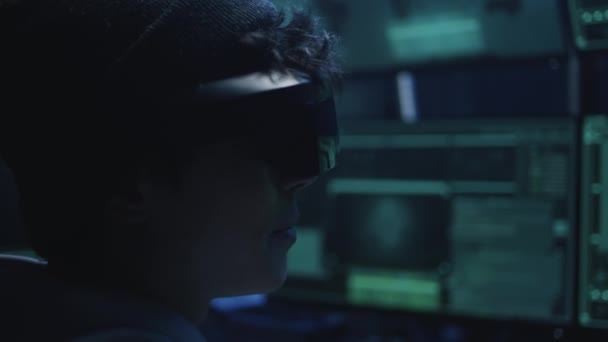 VR gözlüklü genç hacker karanlık odada konuşuyor. — Stok video