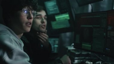 Bilgisayar kullanan ve konuşan erkek hackerlar.