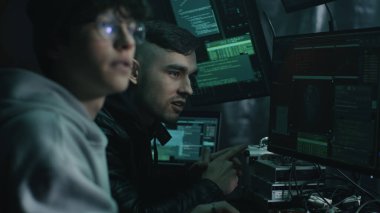 Bilgisayar kullanan ve konuşan erkek hackerlar.