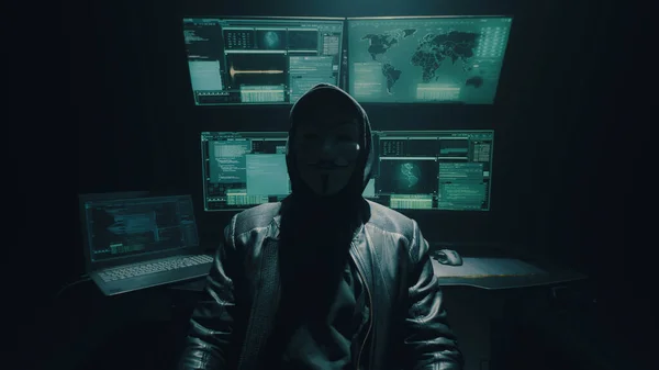 Nierozpoznany cyberprzestępca siedzący w pobliżu komputerów — Zdjęcie stockowe