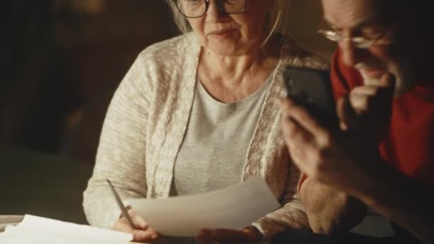 Elderly couple calculating utility payments and joking — Stock Video