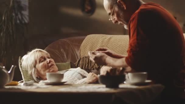 Senior man meten temperatuur en het geven van thee aan vrouw — Stockvideo