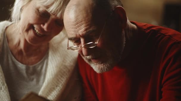 Älteres Paar begutachtet gemeinsam Fotos — Stockvideo