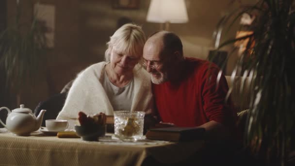 Senior par undersöker bilder nära bordet — Stockvideo