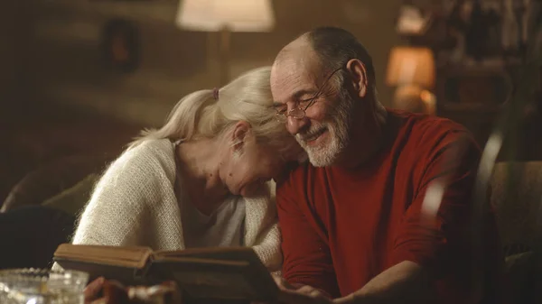 Happy aged couple discussing photos on sofa — Stock Photo, Image