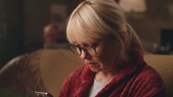 Elderly woman reading shocking news on smartphone — Stock Video