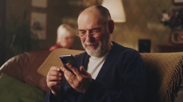 Homem sênior feliz usando telefone celular no sofá — Vídeo de Stock