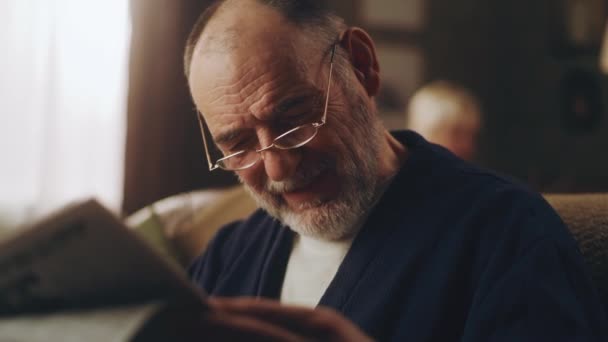 Großvater liest Zeitung auf dem Sofa — Stockvideo