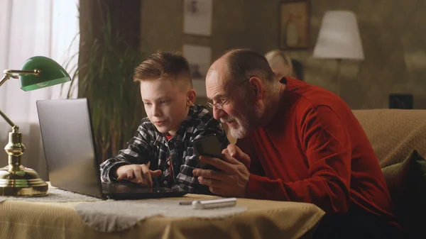 Vnuk pomáhá dědovi používat zařízení — Stock fotografie
