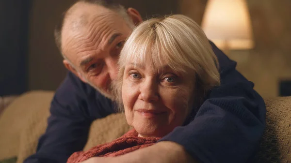 Älterer Mann umarmt Ehefrau auf Sofa — Stockfoto