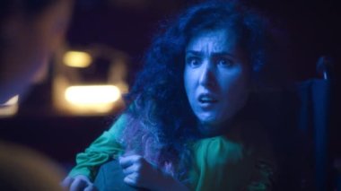 An actress with spinal muscular atrophy emotionally playing a role while a male director interrupting a rehearsal of a play, in the theater and giving recommendations for acting.