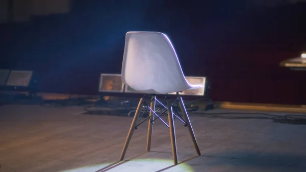 After a rehearsal the directors chair standing on a dim stage illuminated by a spotlight in a theater with empty rows of chairs