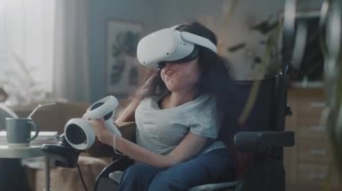 At home woman with disability in a wheelchair wearing virtual reality headset with controllers connect to metaverse and looking around
