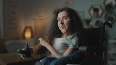 Cheerful happy woman with disability sitting in a motorized wheelchair at cozy home in free time smiling and looking at the camera and smiling
