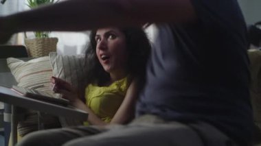 Woman with a disability and man sitting on a sofa at home and discussing drawing in illustration app on digital tablet computer