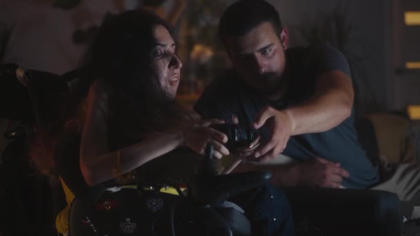 Man Helping Woman Spinal Muscular Atrophy Wheelchair Use Gamepad Playing — Vídeo de stock
