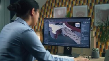 Kadın evden uzaktan çalışırken 3D modelleme programı ile modern kişisel bilgisayar kullanarak 3 boyutlu elektro gitar prototipi tasarlıyor.