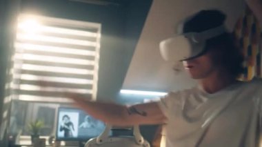 Evdeki adam dijital dünyayı deneyimliyor ve video oyunu oynuyor VR gözlükleri ve kontrolörleri kullanarak. Sanal gerçeklik cihazı. Siber uzay ve metaevren
