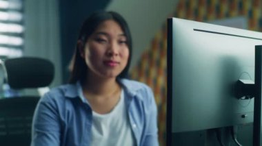 Asyalı kadın ev ofisinin masasında oturuyor ve kişisel bilgisayarda uzaktan çalışıyor ya da boş zamanlarında internette geziniyor.