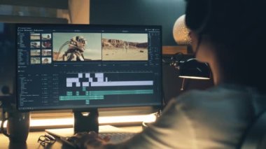 Kulaklıklı erkek editör geceleri masada oturuyor ve profesyonel programda uzaktan çalışırken astronotlar için astronotlarla video düzenliyor.