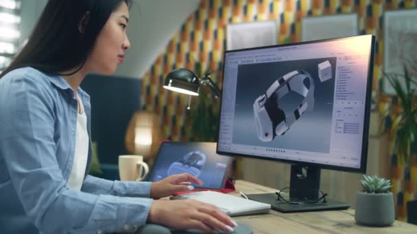 自宅でリモートでプロジェクトに取り組んでいる間 コンピュータやタブレットを使用してVrゴーグルの3Dモデルを作る女性アジアの3Dデザイナーに焦点を当てました フリーランス — ストック動画