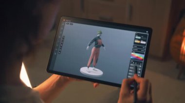 Erkek 3D tasarımcı serbest çalışma projesi üzerinde çalışırken tablet bilgisayar ve dijital kalem kullanarak 3D modelleme uygulamasında kıyafet tasarımı yapıyor