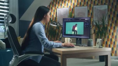 Kişisel bilgisayardaki müşteriler için Photoshop 'ta fotoğraf düzenleyen Asyalı bir kadın ana ofiste oturmuş uzaktan çalışıyor.