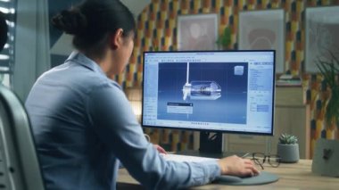 Asyalı kadın mühendis, merkez ofisteki proje üzerinde çalışırken profesyonel 3B modelleme programında rüzgar türbini çiziyor.