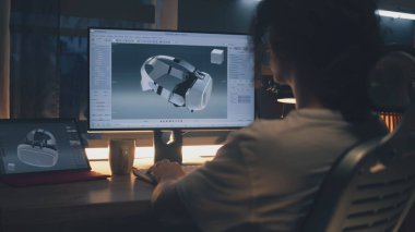 Evden çalışan ve bilgisayar ve dijital tablet kullanarak profesyonel 3D modelleme yazılımında modern VR gözlüklerinin 3 boyutlu prototipini yapan genç bir erkek.