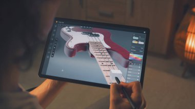 Uzaktan çalışan ve dijital tablet bilgisayar ve stylus kullanarak profesyonel programda 3 boyutlu gitar prototipi yapan adam