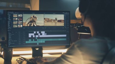 Profesyonel programda astronotlarla video montajı yapan kulaklıklı adam evde bilgisayar başında çalışıyor.