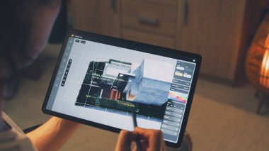 Erkek 3D tasarımcı, dijital tablet bilgisayar ve kalem kullanarak akıllı ev modelleme uygulamasında uzaktan bağımsız olarak çalışıyor.