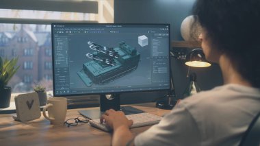 Erkek 3D modelleme projesinde çalışıyor ve profesyonel bilgisayar programında dış modellik yapıyor. Akşamları evde masada otururken bilgisayar kullanıyor..