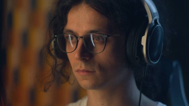 Evde kulaklıklı ve gözlüklü bir adam uzaktan bağımsız bir proje üzerinde çalışıyor ya da boş zamanlarında internette gezinip müzik dinliyor.