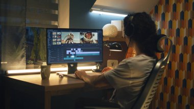 Profesyonel programda astronotlarla video montajı yapan kulaklıklı adam evde bilgisayar başında çalışıyor.