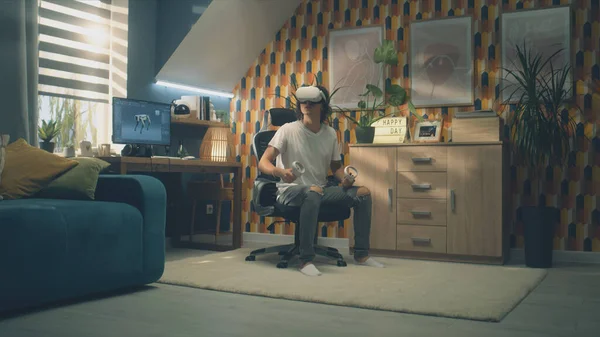 男は彼の部屋で余暇の時間に現代的なVrヘッドセットとワイヤレスコントローラを使用してビデオゲームをプレイ 仮想現実デバイス サイバー空間と方法論 — ストック写真