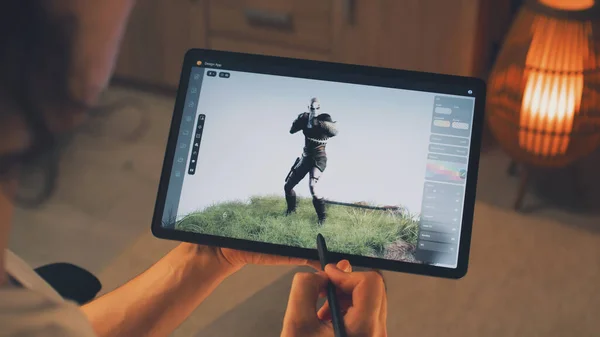 Male 3D designer creating 3D animation of video game character in design application on modern digital tablet computer using stylus