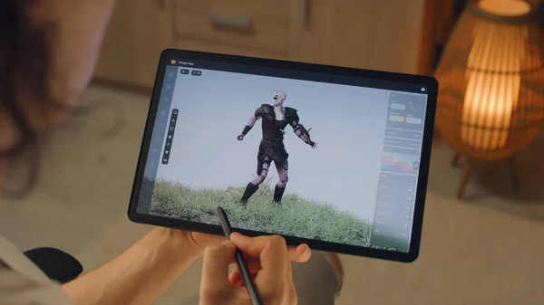 Male 3D designer creating 3D animation of video game character in design application on modern digital tablet computer using stylus