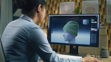 Kadın tasarımcı evden uzaktan çalışırken bilgisayar ve profesyonel yazılım kullanarak kıyafetlerin 3 boyutlu görselleştirmesini yapıyor