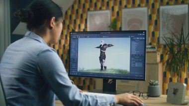 Asyalı kadın 3D tasarımcı video oyunu karakteri için animasyon yapıyor. Modern bilgisayar ve 3D modelleme projeleri için yazılım kullanıyor.