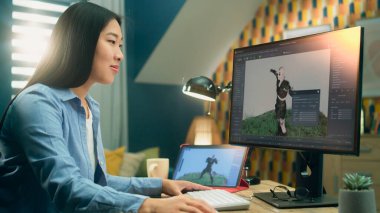 Asyalı kadın 3D tasarımcı bilgisayar ve bilgisayar kullanarak 3D proje üzerinde çalışırken video oyunu karakteri için görsel ve animasyon yaratıyor