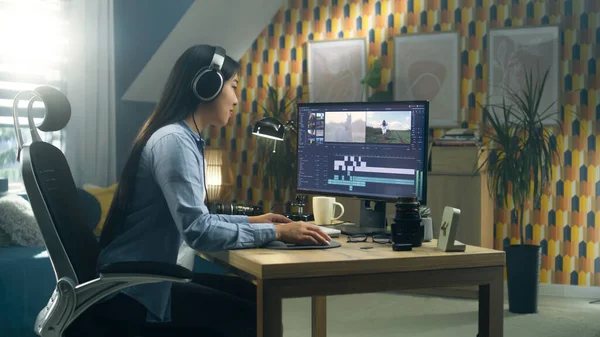 Asian woman sitting at the desk in headphones at home office and editing video for blog in professional program on computer. Freelance