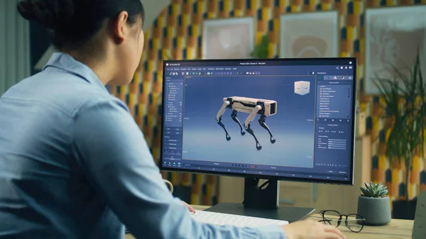 Asian woman working on pc in 3D modeling program remotely from home office and creating 3D prototype of modern robot