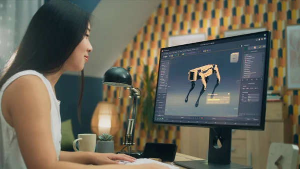 Asian woman working on pc in 3D modeling program remotely from home office and creating 3D prototype of modern robot