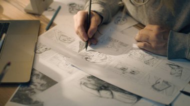 Kalem çizimleri yapan bir kadının yakın çekim elleri. Ev tabanlı bir tasarım stüdyosunda çizim tahtası üzerinde çalışıyorum. Kadın video için yol haritası olarak çizimler yapıyor. Hikaye anlatma.
