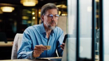 Telefon kullanan iş adamı, banka kartından para transfer eden, modern bilişim şirketinin ofisinde çalışırken internet üzerinden hizmet ödeyen.