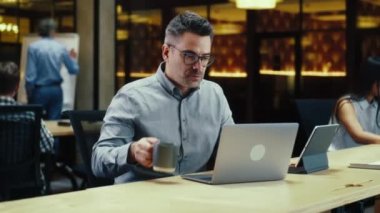 Erkek ofis çalışanı, tablet bilgisayar ve dizüstü bilgisayar kullanıyor, klavyede daktilo kullanıyor, modern ofiste başlangıç projesi veya iş stratejisi üzerinde çalışıyor. IT şirketinin web sitesini geliştiren programcı