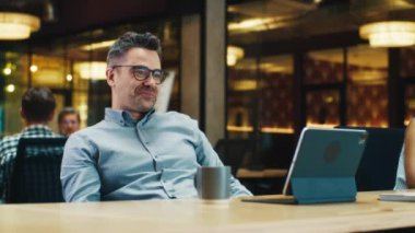 Adam müşteriyle online konuşuyor, dijital tablet bilgisayarda video görüşmesi yapıyor, pazarlama şirketinin modern ofisinde çalışıyor. Çevrimiçi iş toplantısı. Ürünlerin reklamı ve satışı